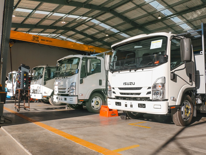 Four identical water utilities trucks lined up in a workshop, almost ready to be delivered to the customer.