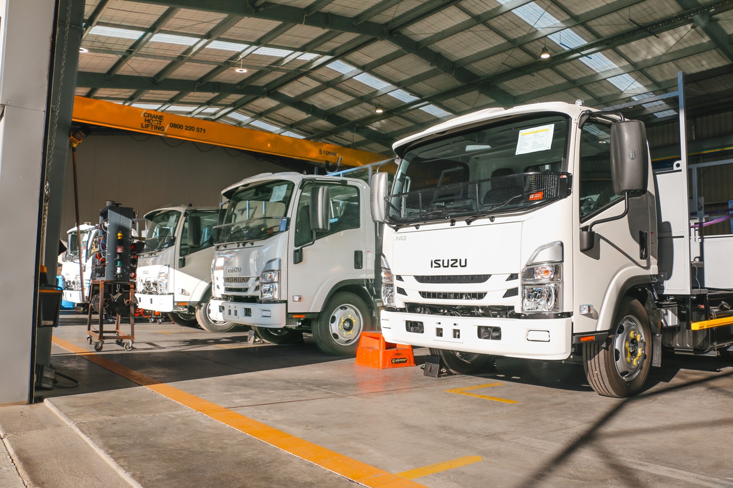 Four identical water utilities trucks lined up in a workshop, almost ready to be delivered to the customer.