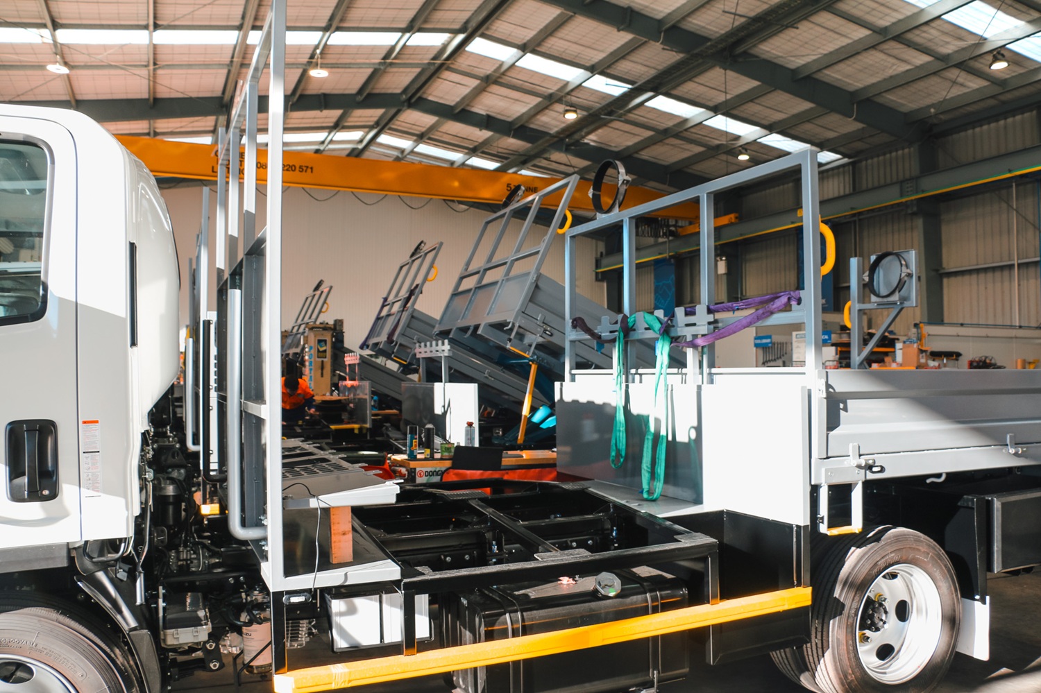Four identical water utilities trucks lined up in a workshop, almost ready to be delivered to the customer.