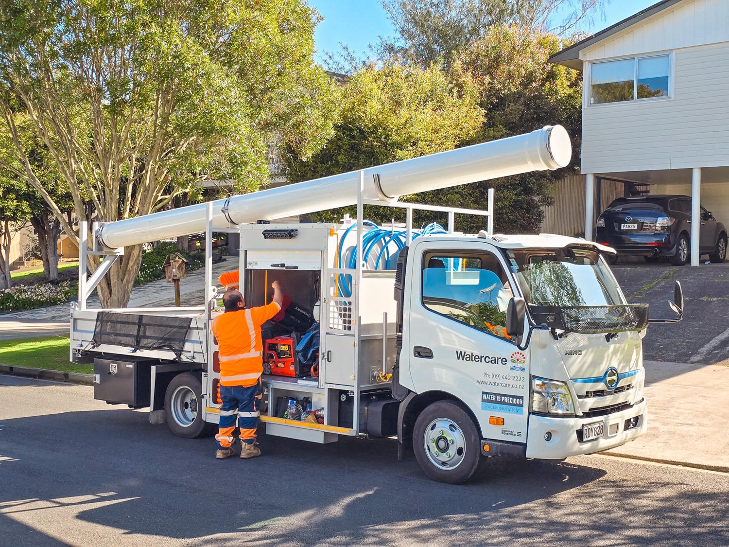 Four identical water utilities trucks lined up in a workshop, almost ready to be delivered to the customer.